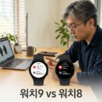 책상 위에 나란히 놓인 두 개의 둥근 스마트워치와 이를 비교하는 40대 한국인 남성